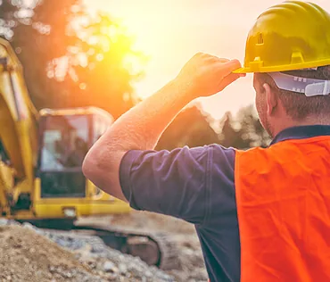 Profissional de capacete em canteiro de obras com escavadeira